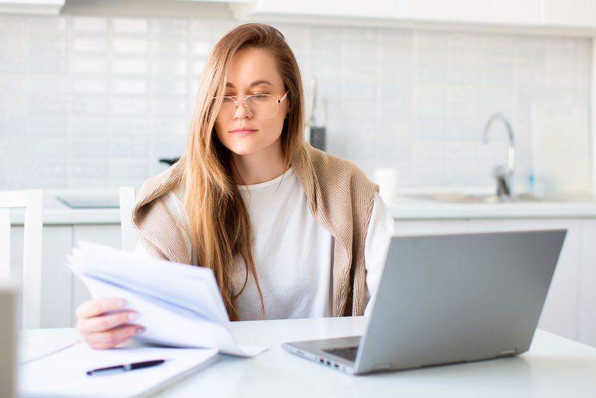 A woman reading papers while infront of her laptop